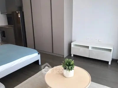 Modern studio apartment with sleek furniture and minimalist design, featuring a cozy bed and stylish kitchenette.