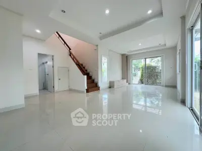 Spacious modern living room with staircase and large windows offering garden view