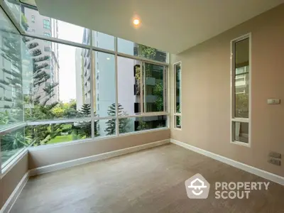 Spacious corner unit with floor-to-ceiling windows offering lush garden views in modern apartment.