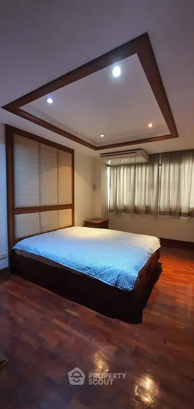 Spacious bedroom with modern ceiling design and wooden flooring