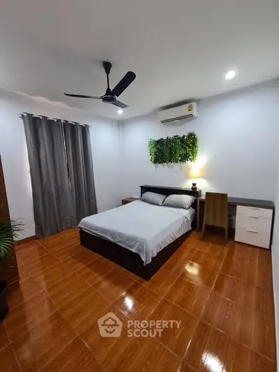 Cozy bedroom with modern decor, featuring a comfortable bed, air conditioning, and stylish wooden flooring.
