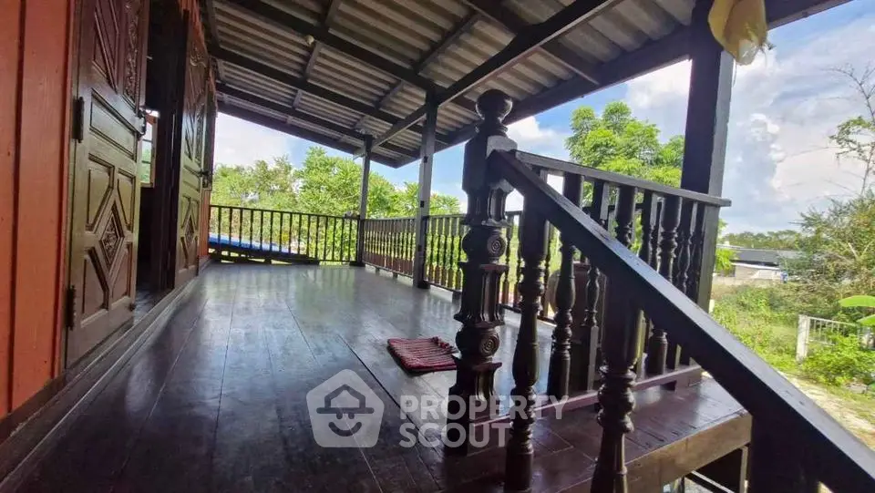 Charming wooden balcony with scenic garden view, perfect for relaxation and outdoor enjoyment.
