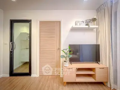 Modern living room with sleek TV stand and glass door leading to kitchen.