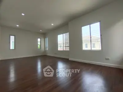 Spacious empty living room with hardwood floors and large windows