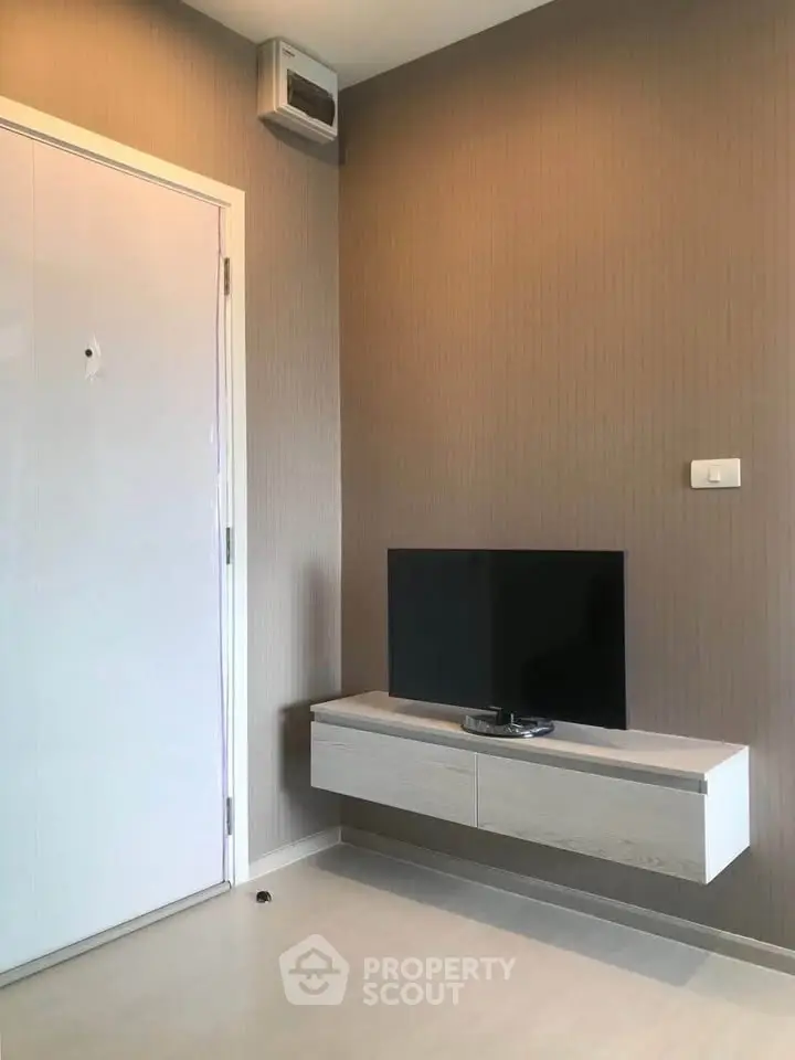 Modern minimalist living room with wall-mounted TV and sleek storage unit.