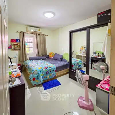 Cozy bedroom with mirrored wardrobe and colorful bedding in a modern apartment.