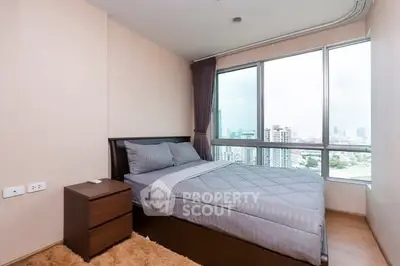 Cozy bedroom with city view and modern furnishings in high-rise apartment.