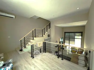 Spacious modern living room with mezzanine and stylish staircase, featuring open layout and natural light.