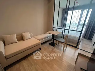 Modern studio apartment with wooden flooring and cozy furniture, featuring a partitioned bedroom area.