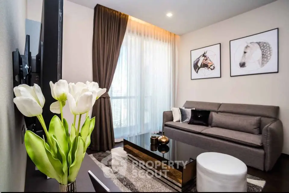 Modern living room with stylish decor and large window, featuring a cozy sofa and elegant tulip arrangement.