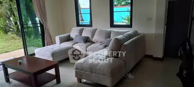 Spacious living room with modern sectional sofa and garden view, perfect for relaxation and entertaining.