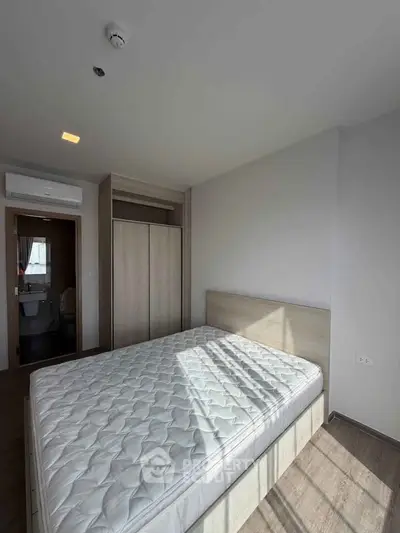 Modern bedroom with natural light and minimalist design, featuring a comfortable bed and built-in wardrobe.