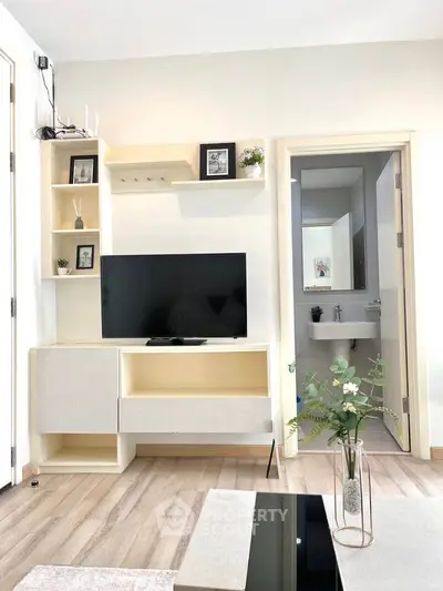 Modern living room with sleek TV unit and open bathroom view, featuring minimalist decor and light wood flooring.