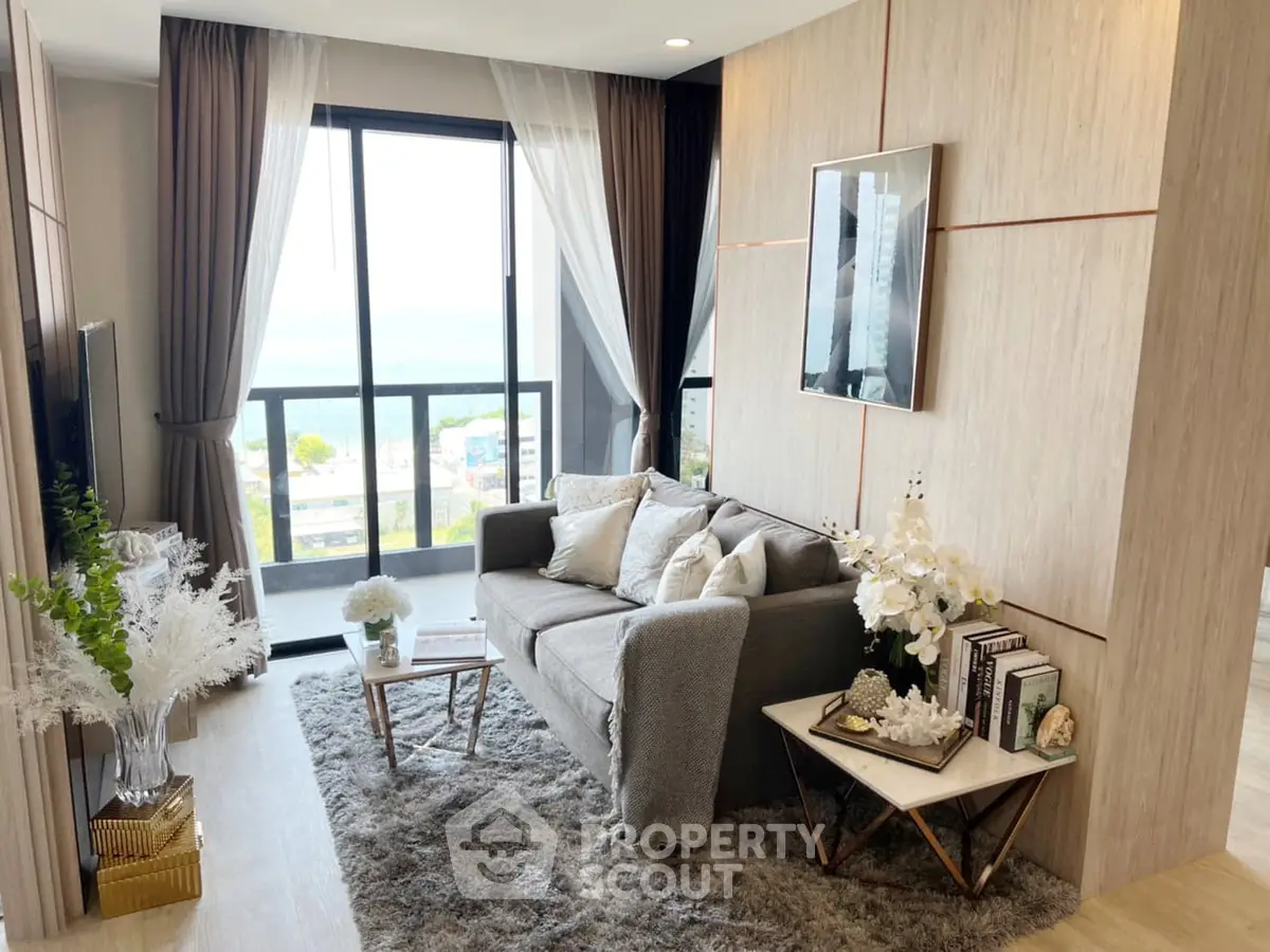 Elegant living room with plush grey sofa, chic decor, and floor-to-ceiling windows offering a luminous ambiance and a serene view.