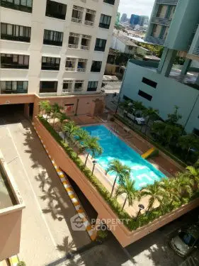 Stunning aerial view of modern apartment complex with inviting pool and lush greenery.