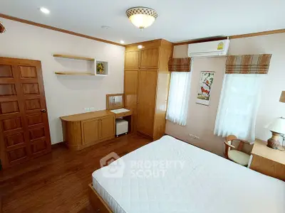 Spacious bedroom with wooden furniture and natural light, featuring a cozy ambiance.