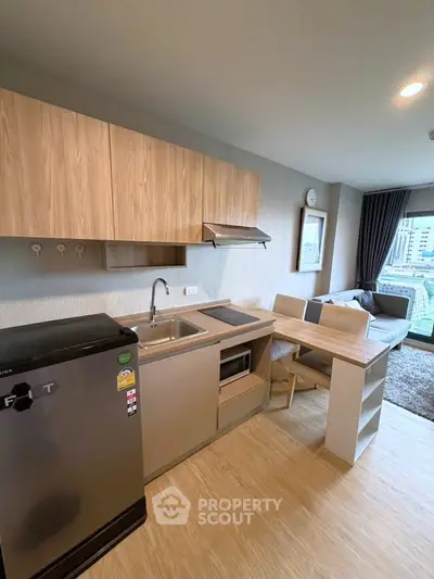 Modern open-layout kitchen with sleek appliances and cozy living area in a stylish apartment.