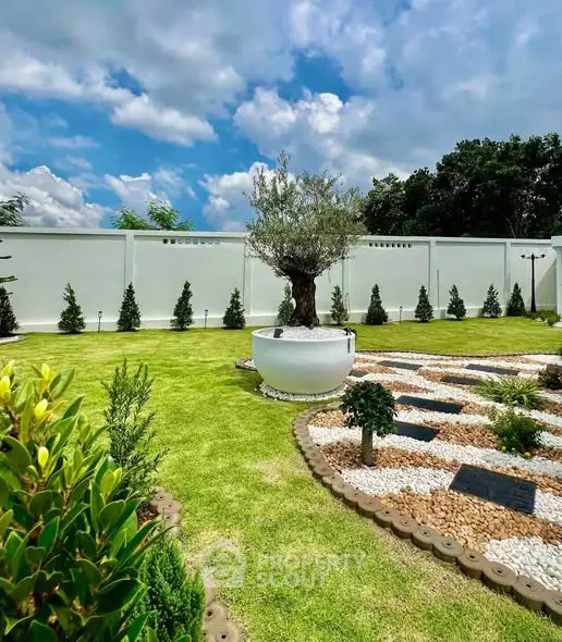 Beautiful landscaped garden with lush greenery and decorative stone pathway under a clear blue sky.