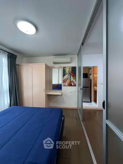 Modern bedroom with blue bedding and sliding closet doors, featuring a stylish wall painting.