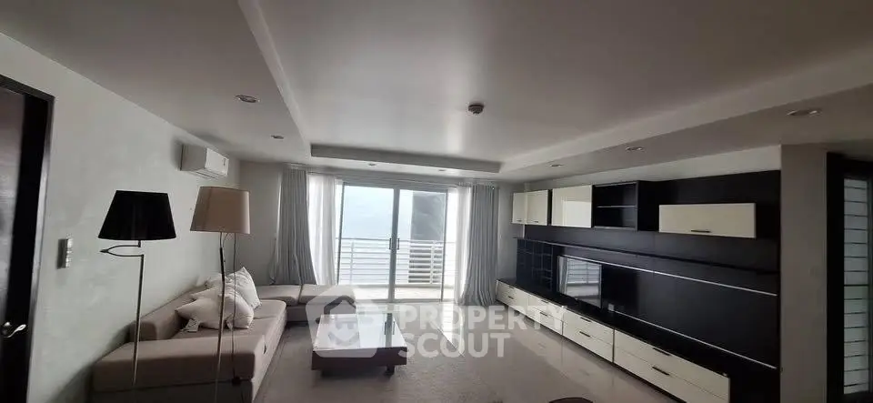 Spacious modern living room with sleek furniture and large windows offering natural light.