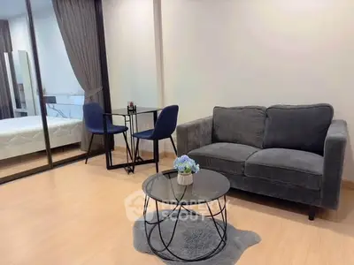 Modern living room with cozy sofa and glass table, adjacent to a stylish bedroom with glass partition.