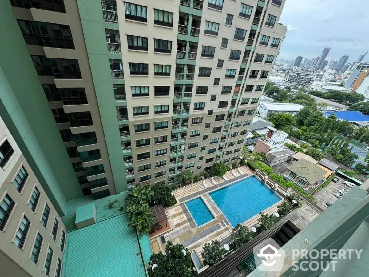 High-rise building with pool and city view from balcony, ideal urban living.