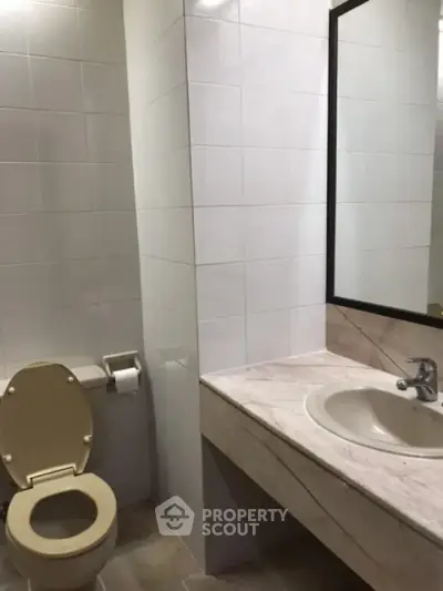 Modern bathroom with tiled walls and marble countertop in a real estate property.