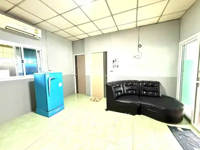 Spacious living room with modern black sofa and vibrant blue refrigerator, ideal for contemporary living.