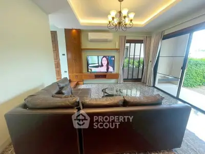 Spacious living room with modern leather sofa and large TV, featuring elegant lighting and garden view.