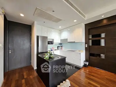 Modern kitchen with sleek design, island, and wooden flooring in a contemporary apartment.
