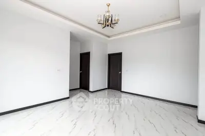 Spacious empty room with elegant chandelier and marble flooring, ready for customization.