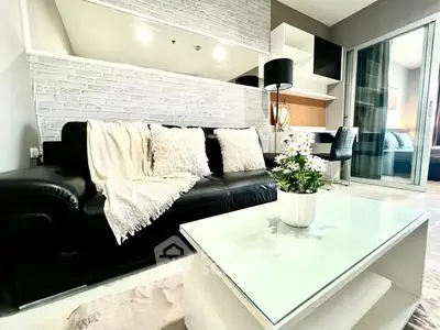 Modern living room with sleek black sofa, stylish decor, and cozy ambiance.