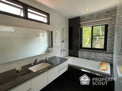 Luxurious modern bathroom with elegant black and white marble finishes and large window view.