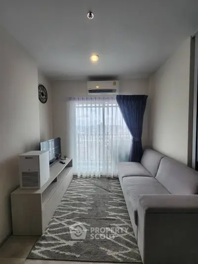 Modern living room with sleek furniture and large window offering natural light.