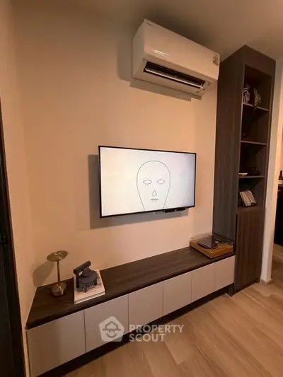 Modern living room with wall-mounted TV and air conditioning unit, featuring sleek storage cabinets.