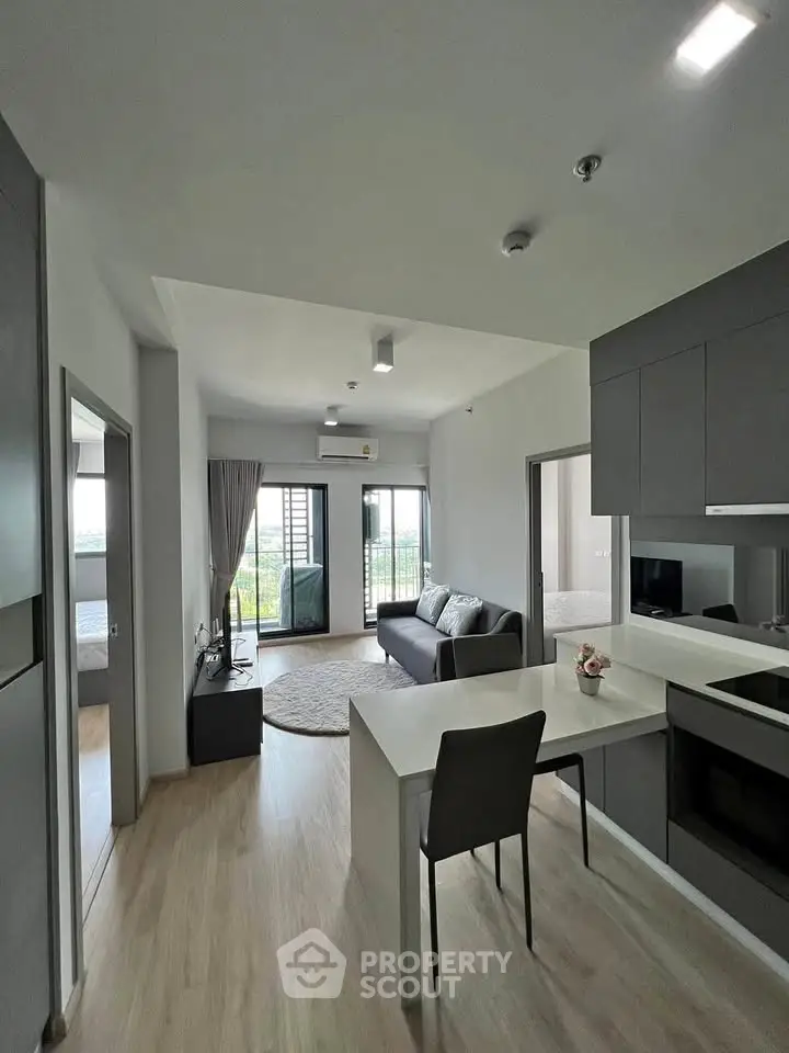 Modern open-plan living room with sleek kitchen and balcony view in stylish apartment.