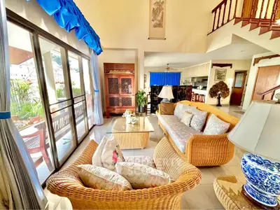 Spacious living room with wicker furniture and large windows opening to a balcony with scenic views.
