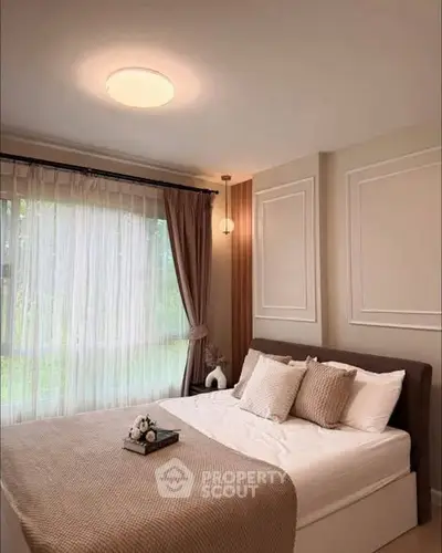 Cozy bedroom with elegant decor and large window offering natural light.