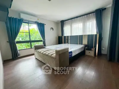Spacious bedroom with large windows and modern decor in a serene setting.