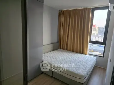 Modern bedroom with large window and city view, featuring a comfortable bed and stylish decor.