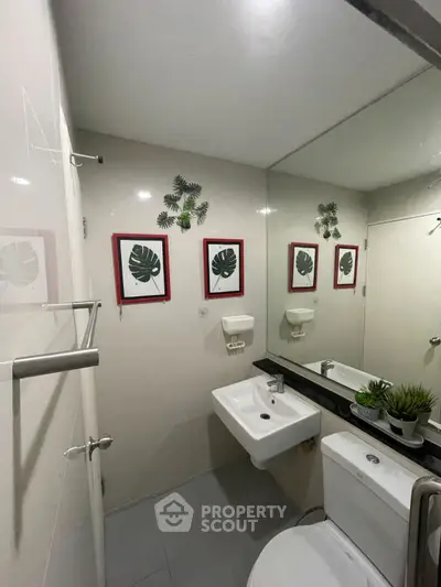 Modern bathroom with stylish decor and wall art, featuring a sleek sink and toilet.