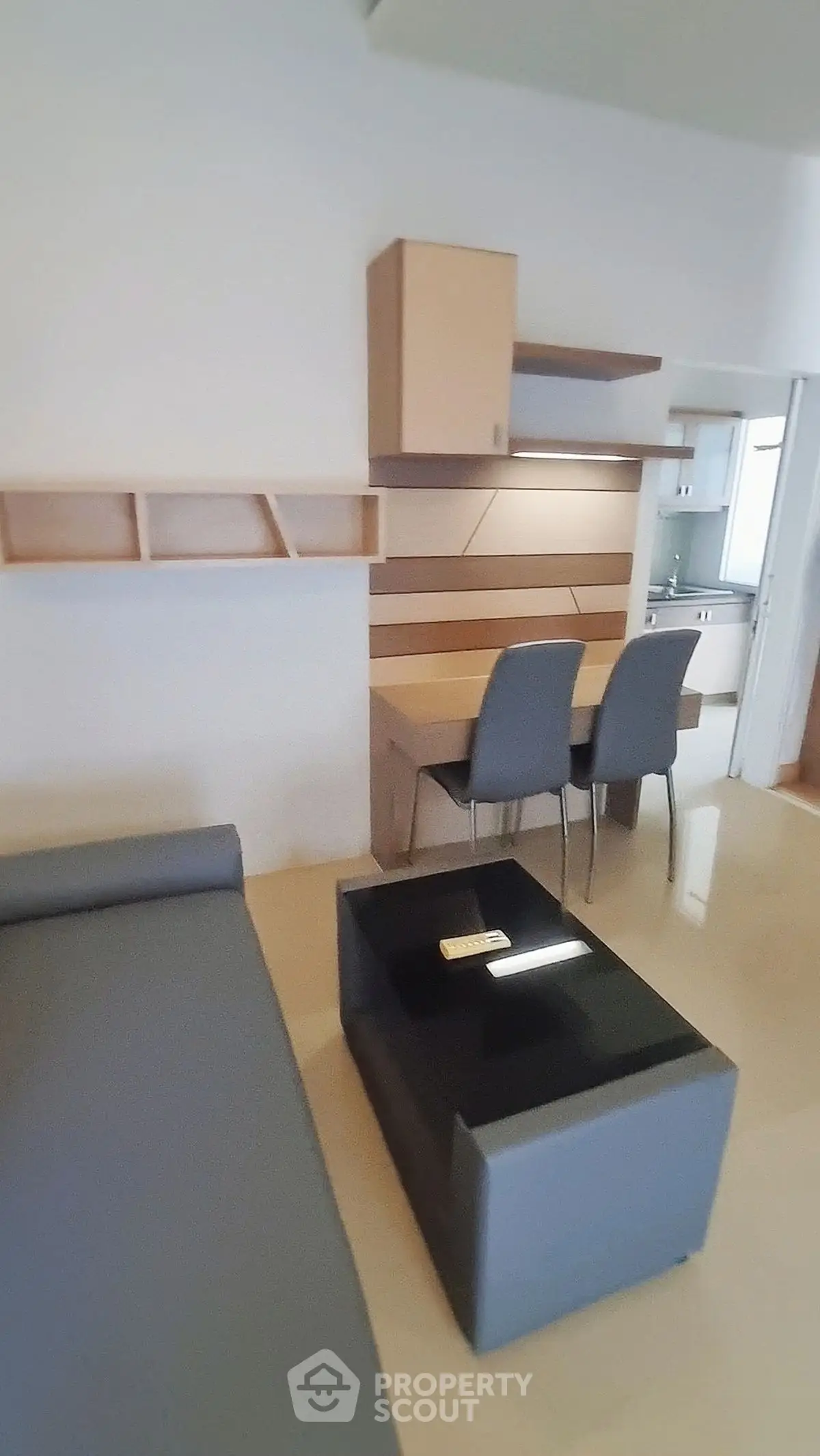 Modern studio apartment with sleek furniture and compact kitchen area.