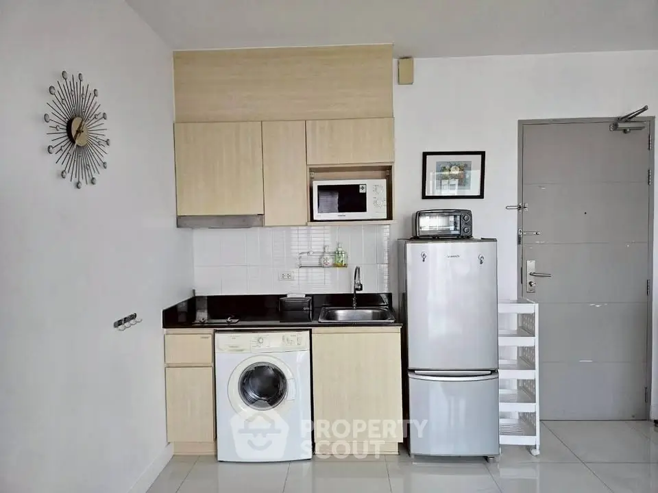 Modern compact kitchen with appliances including washing machine and fridge in a stylish apartment.