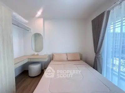 Cozy bedroom with natural light, featuring a stylish vanity and modern decor.