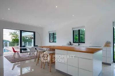 Modern open-plan kitchen and dining area with pool view