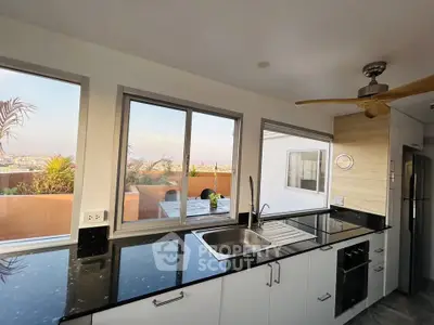 Modern kitchen with sleek black countertops and stunning city view