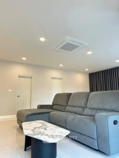 Spacious modern living room with plush gray sofa and stylish marble coffee table.