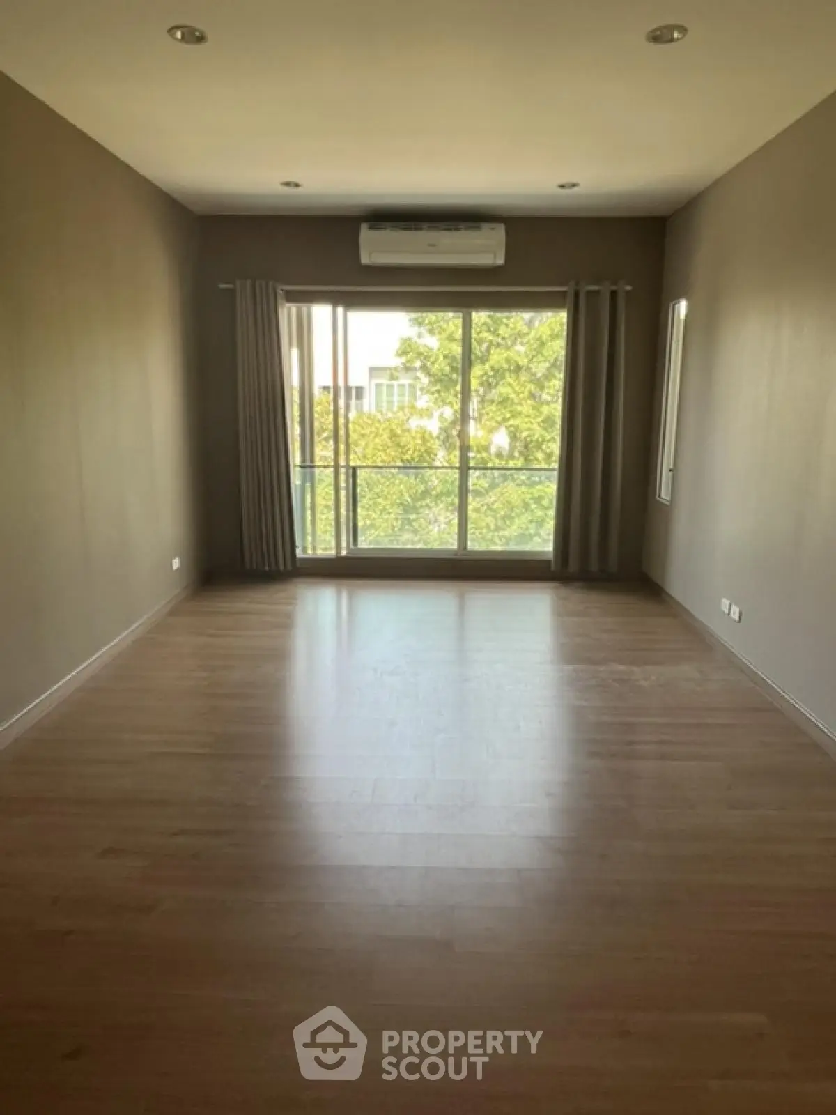 Spacious empty room with large window and air conditioning, perfect for customization.