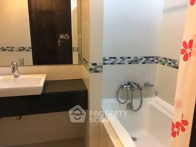 Modern bathroom with sleek sink and bathtub, featuring stylish tile accents.