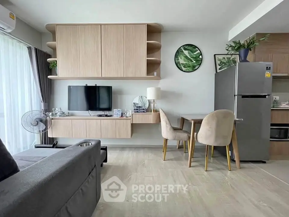 Modern living room with stylish furniture and open kitchen layout, featuring a sleek refrigerator and elegant decor.